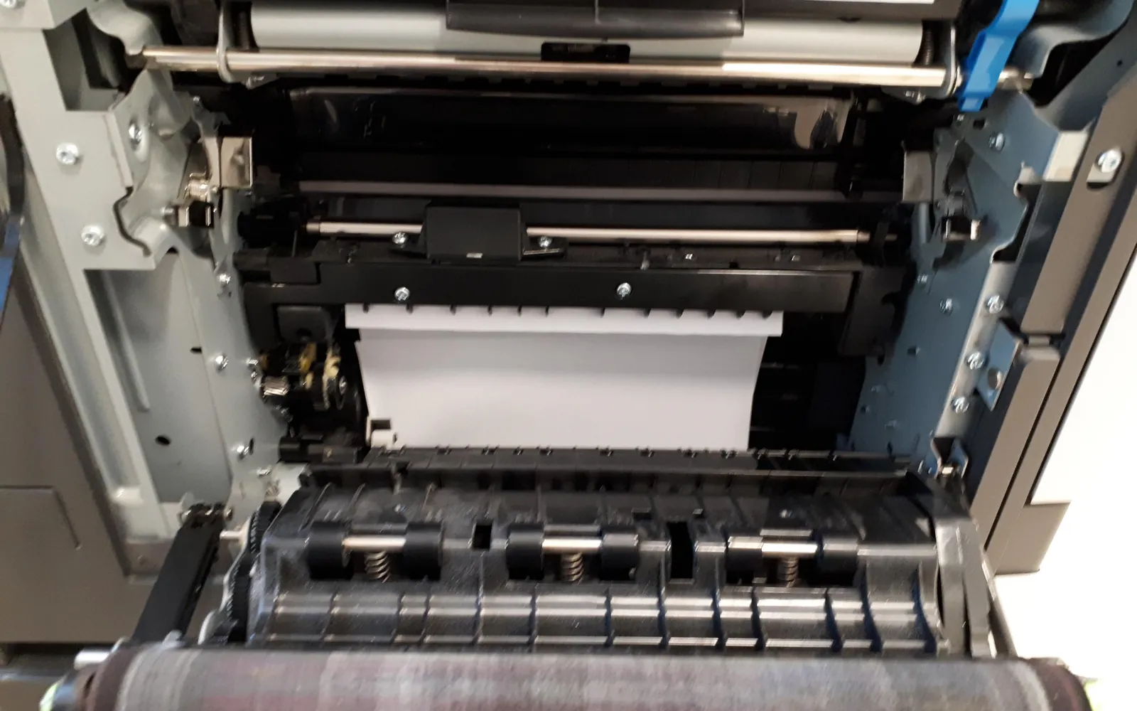 Inside an office laser printer with the cover open, showing rollers and the paper path