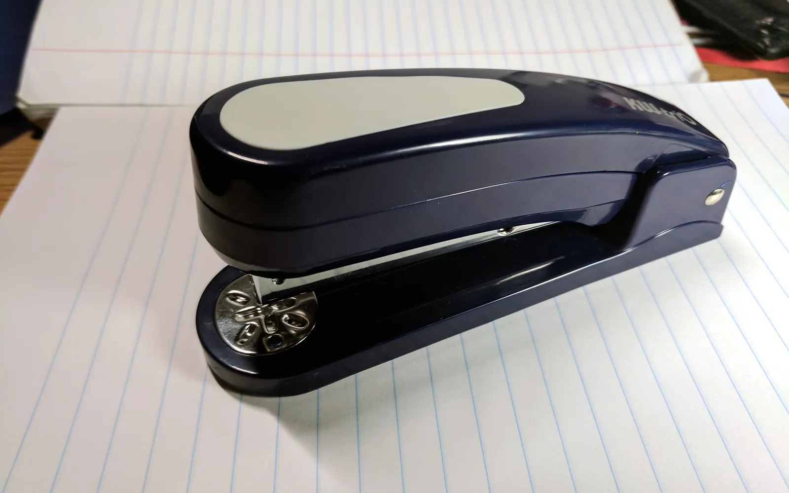 A desktop stapler resting on a stack of printed paper, the manual job a copier finisher automates